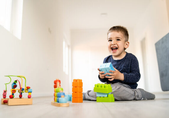 Small boy playing with little brick block toys at home on the floor smiling